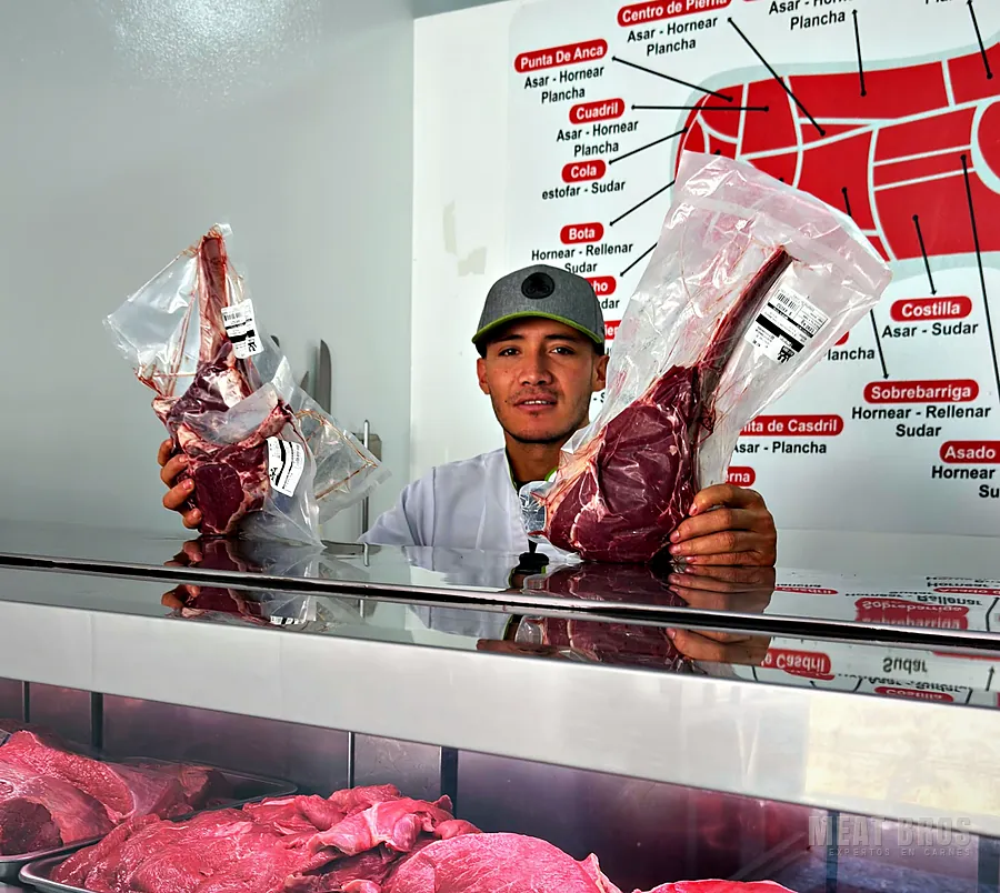 Carnicero de Meat Bros muestra dos tomahawk empacados al vacío sobre la vitrina de la carnicería en Sogamoso