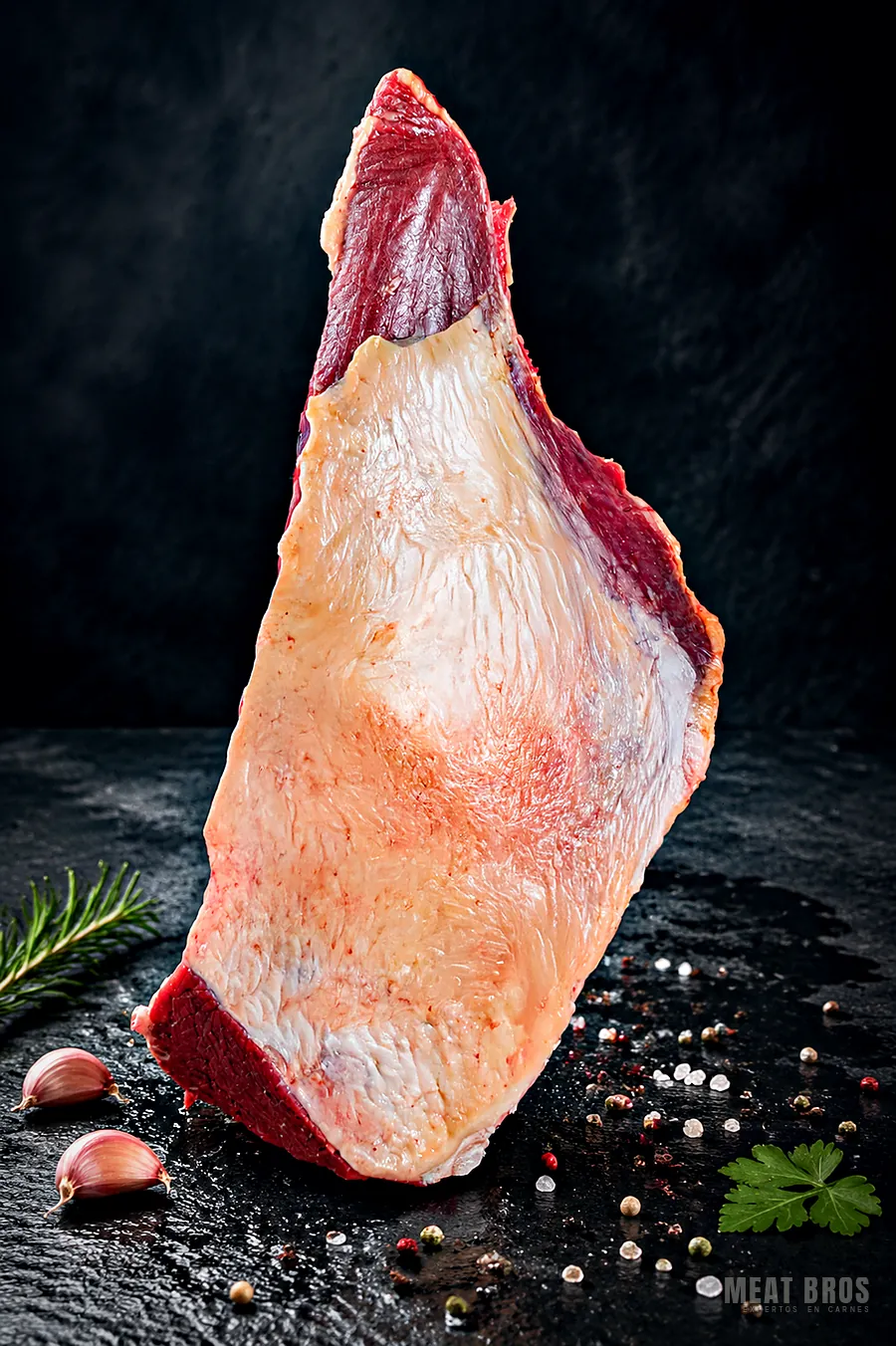 Corte triangular de res con capa de grasa dorada, de pie sobre la piedra